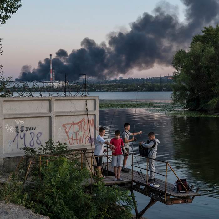 Children with fishing poles, dark smoke in the background.